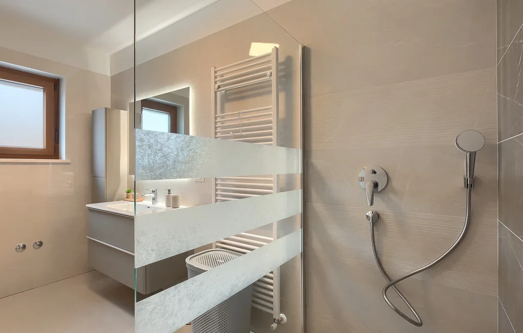 Un baño moderno con una ducha de vidrio y un toallero calefactable.