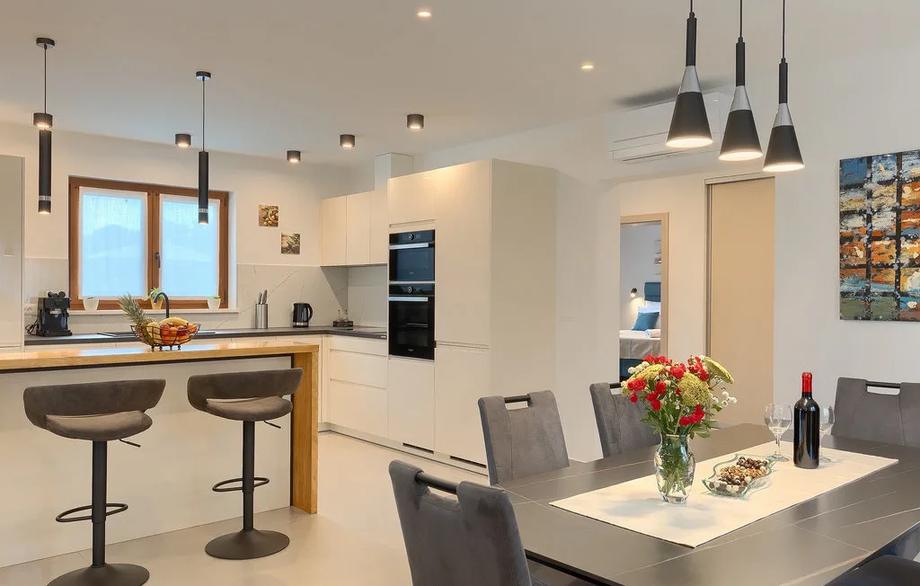 Una cocina moderna y comedor con una barra de desayuno y una mesa.