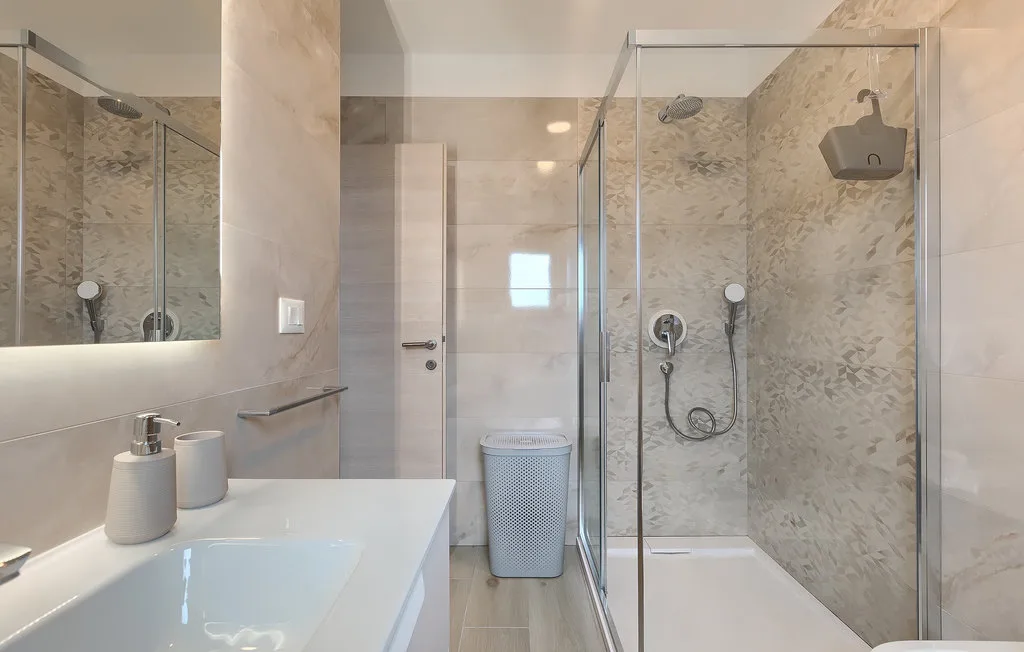 Un baño luminoso con lavabo y ducha con mampara de vidrio.