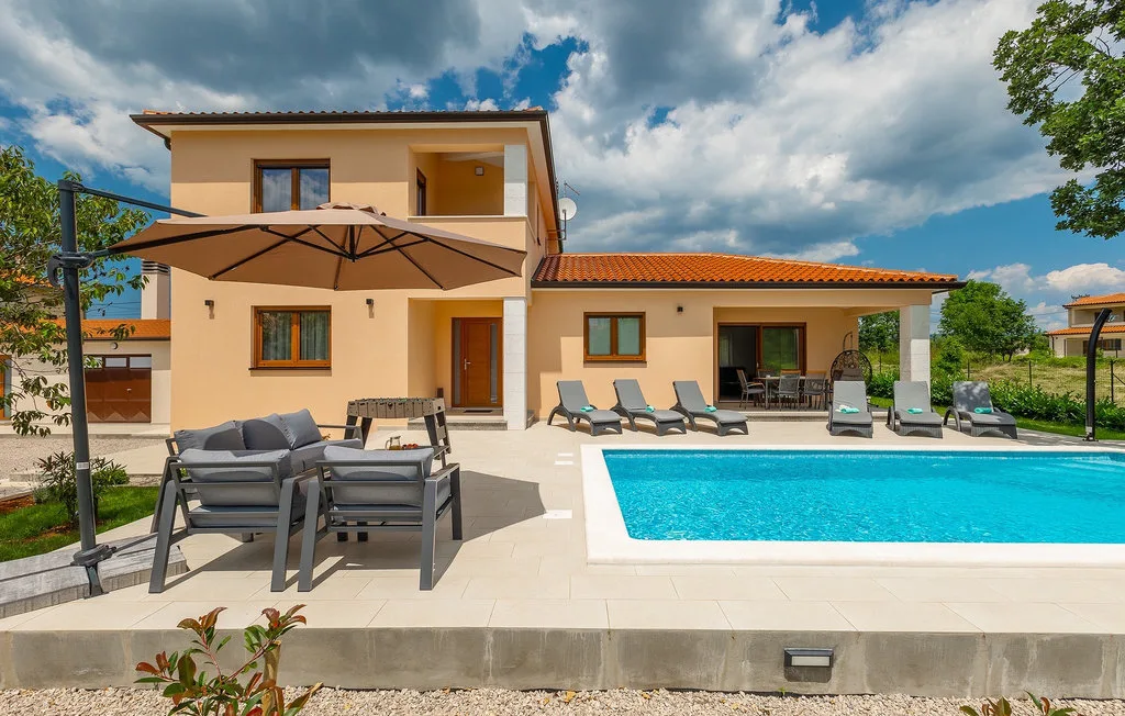 Patio junto a la piscina con asientos al aire libre junto a una casa moderna.