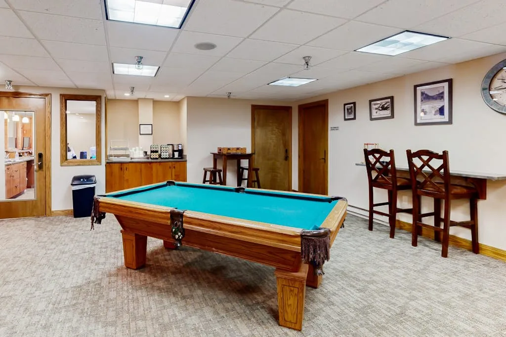 Una sala de recreación tiene una mesa de billar y una mesa de comedor con sillas.