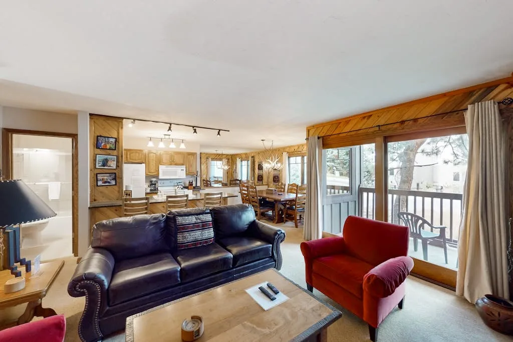 A living room opens into a dining area, with seating beside large windows.