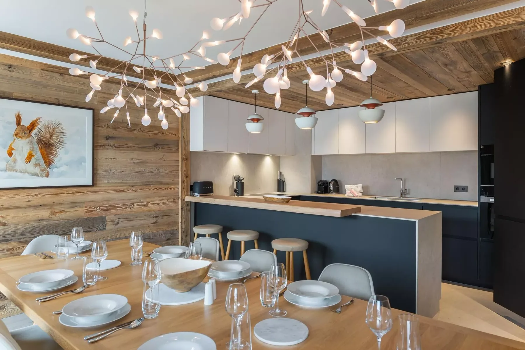 A dining table and kitchen counter sit beneath sculptural pendant lights.