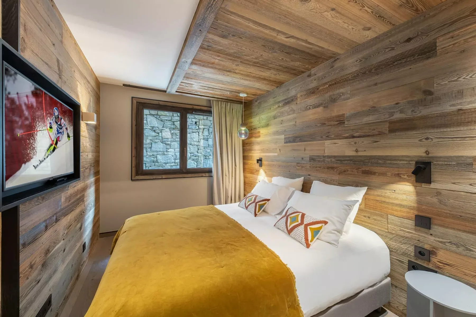 Un dormitorio con una cama vestida con ropa de cama blanca y una manta color mostaza.