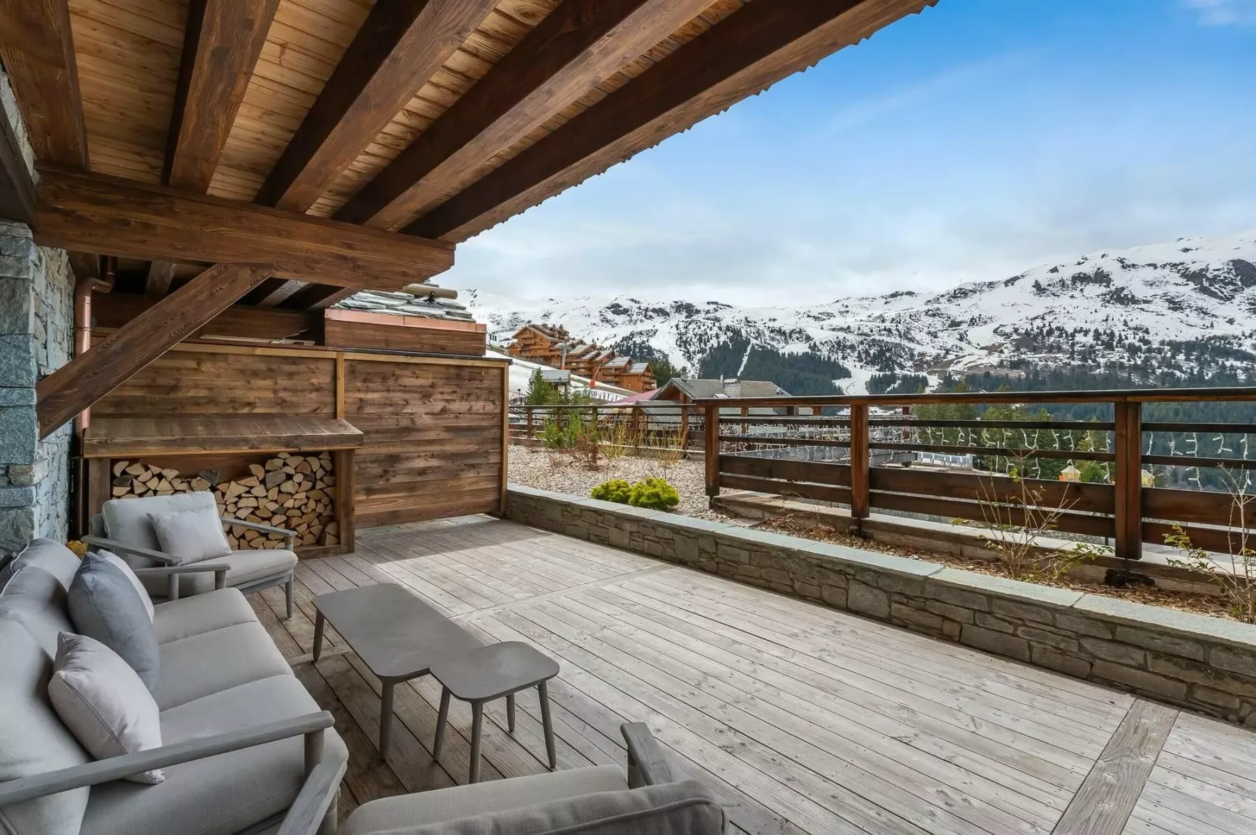 Una terraza de madera con asientos y vistas a montañas nevadas.