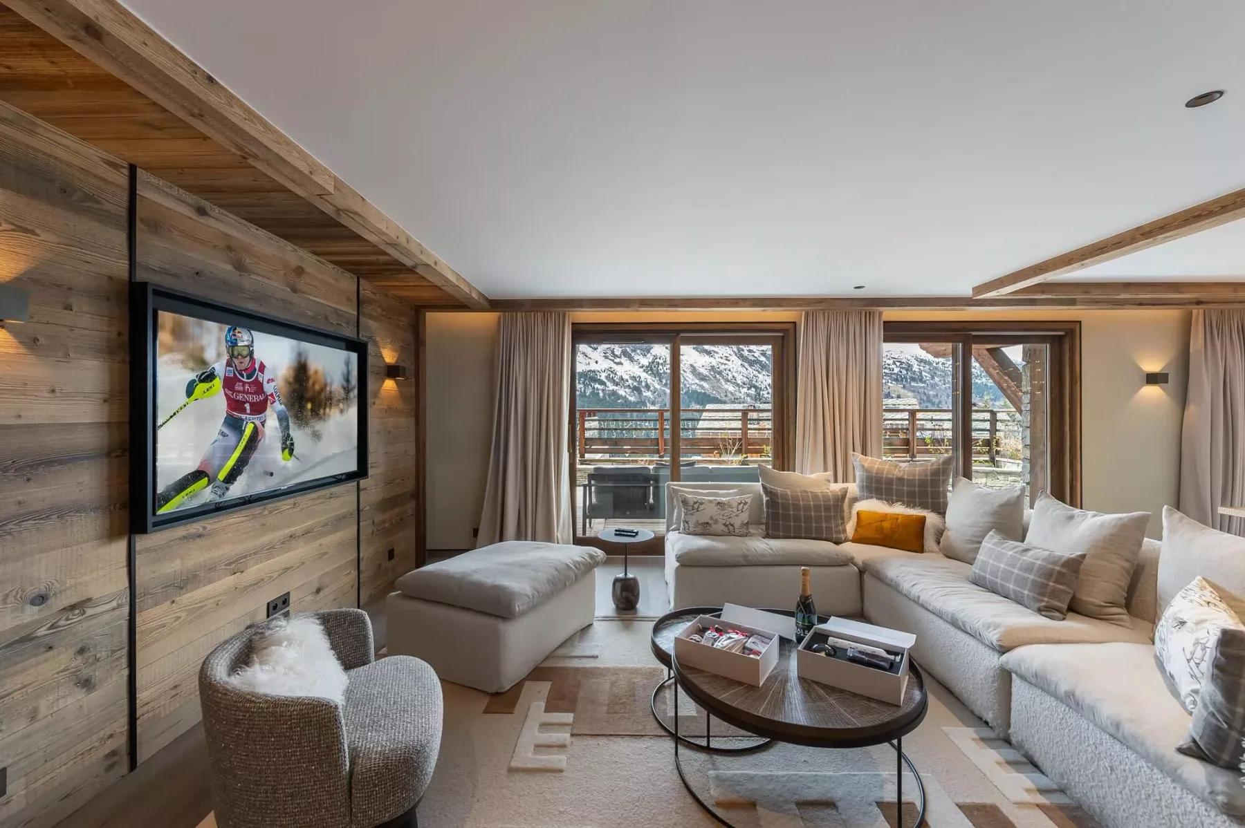 Sala de estar con asientos, un televisor y ventanas con vistas a un paisaje nevado.