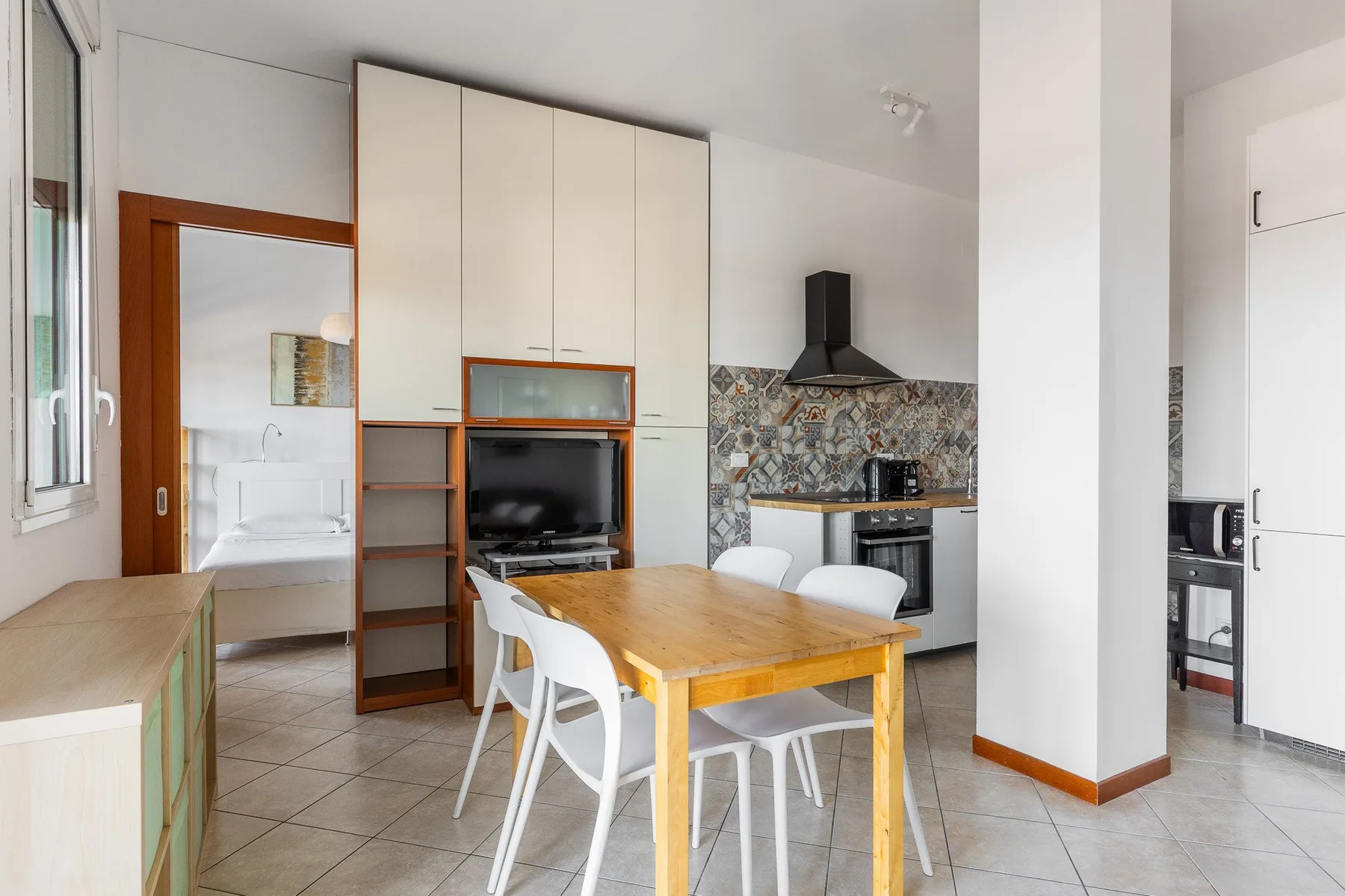Una cocina abierta con zona de comedor, mesa de madera y sillas blancas.