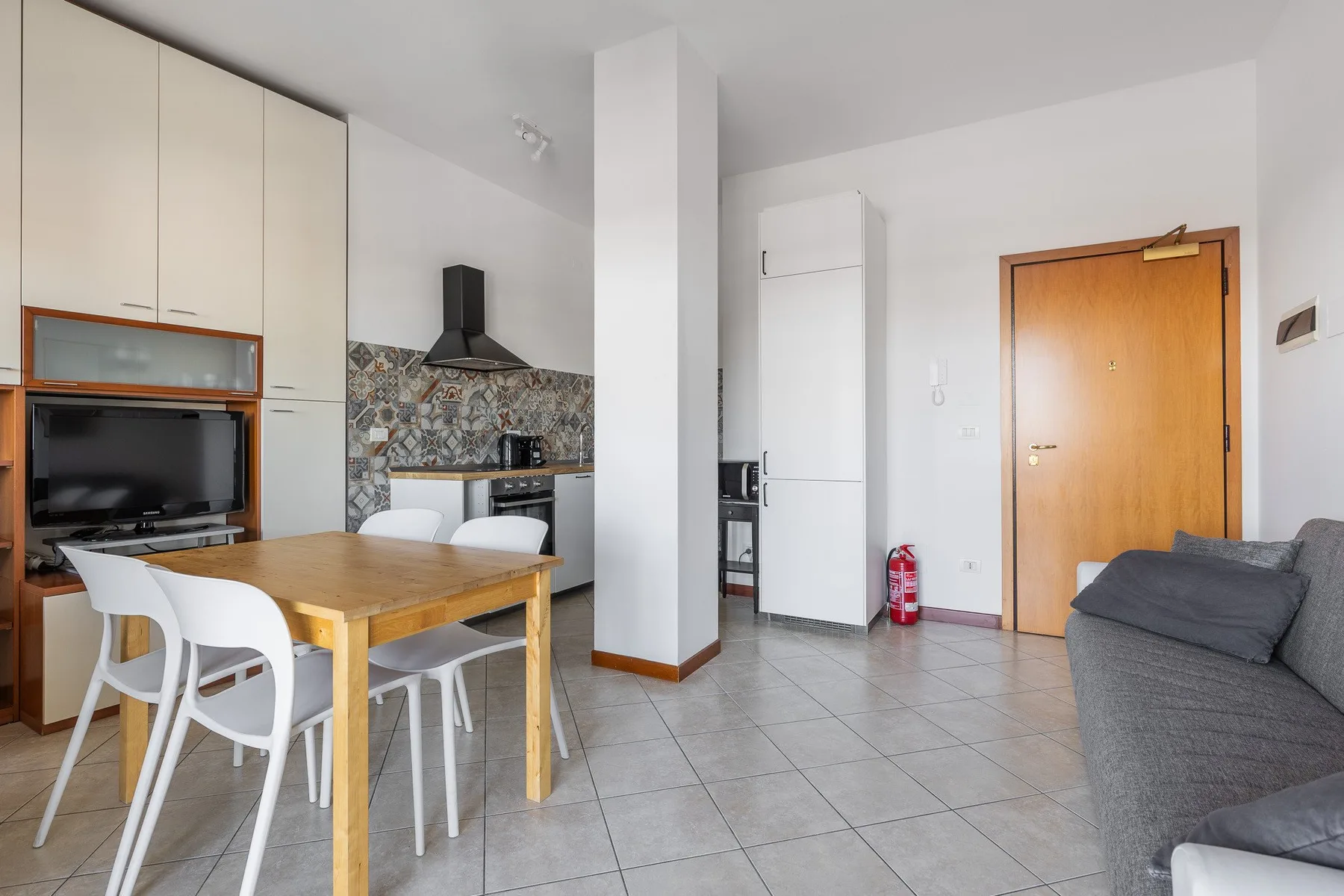 Una luminosa sala-comedor de planta abierta con cocina y asientos grises.
