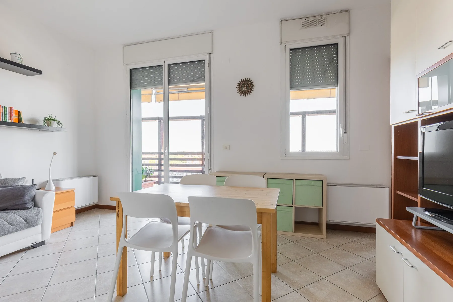 Una luminosa sala de estar y comedor con mesa, sillas y asientos grises.