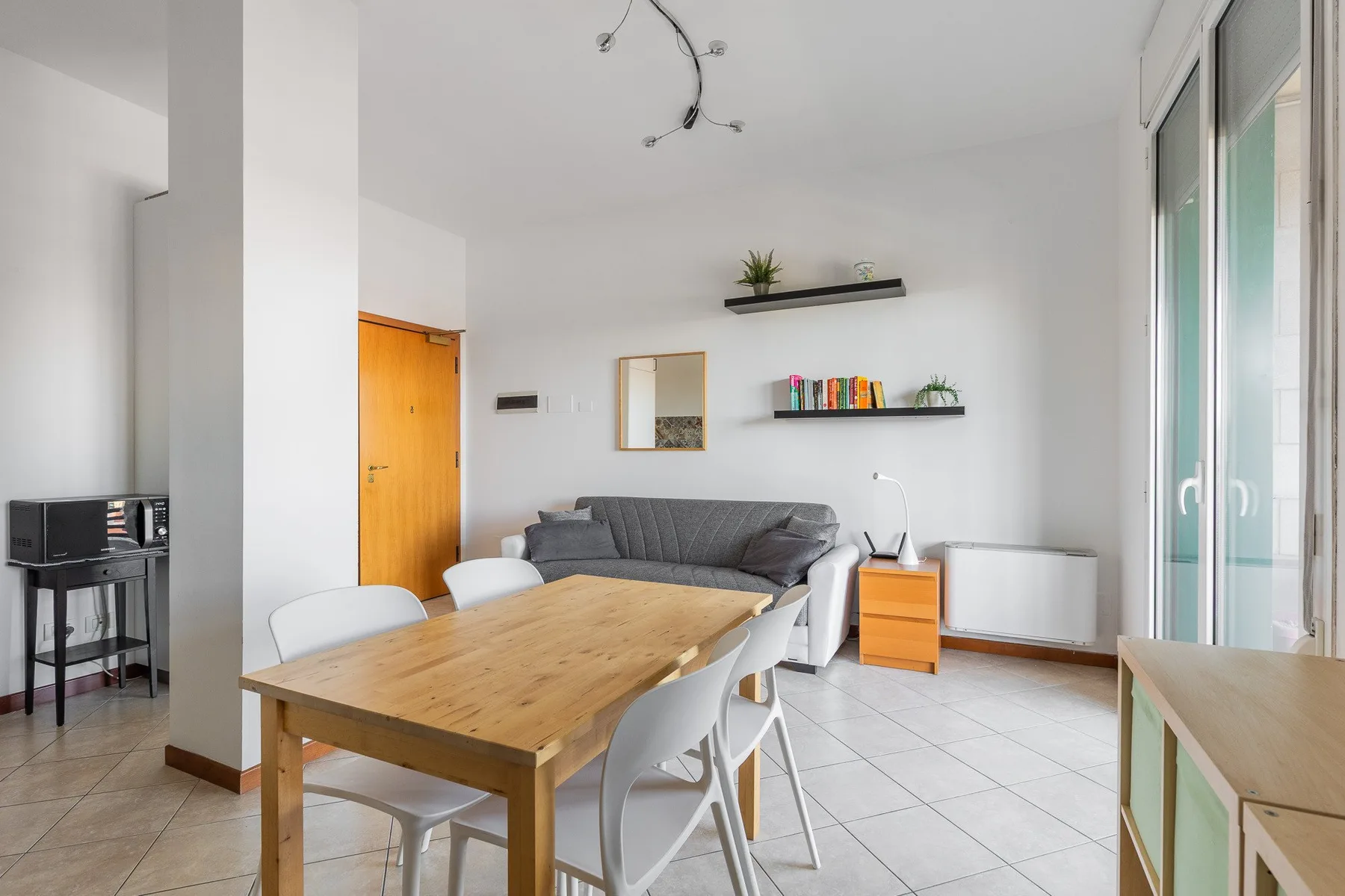 Un comedor y sala de estar luminosos con una mesa de madera, asientos y grandes ventanas.