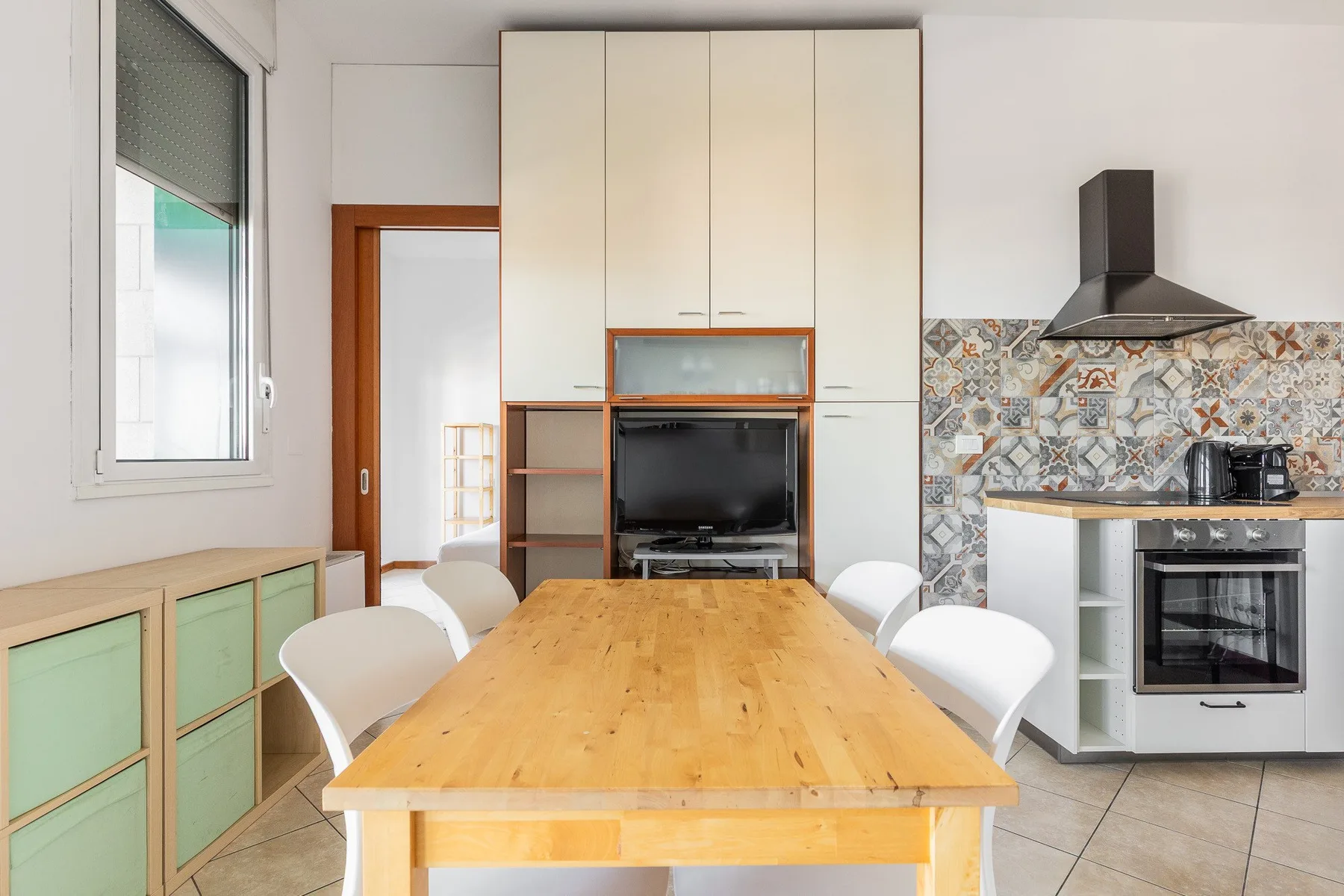 Una mesa de comedor y asientos están frente a una cocina con armarios empotrados.