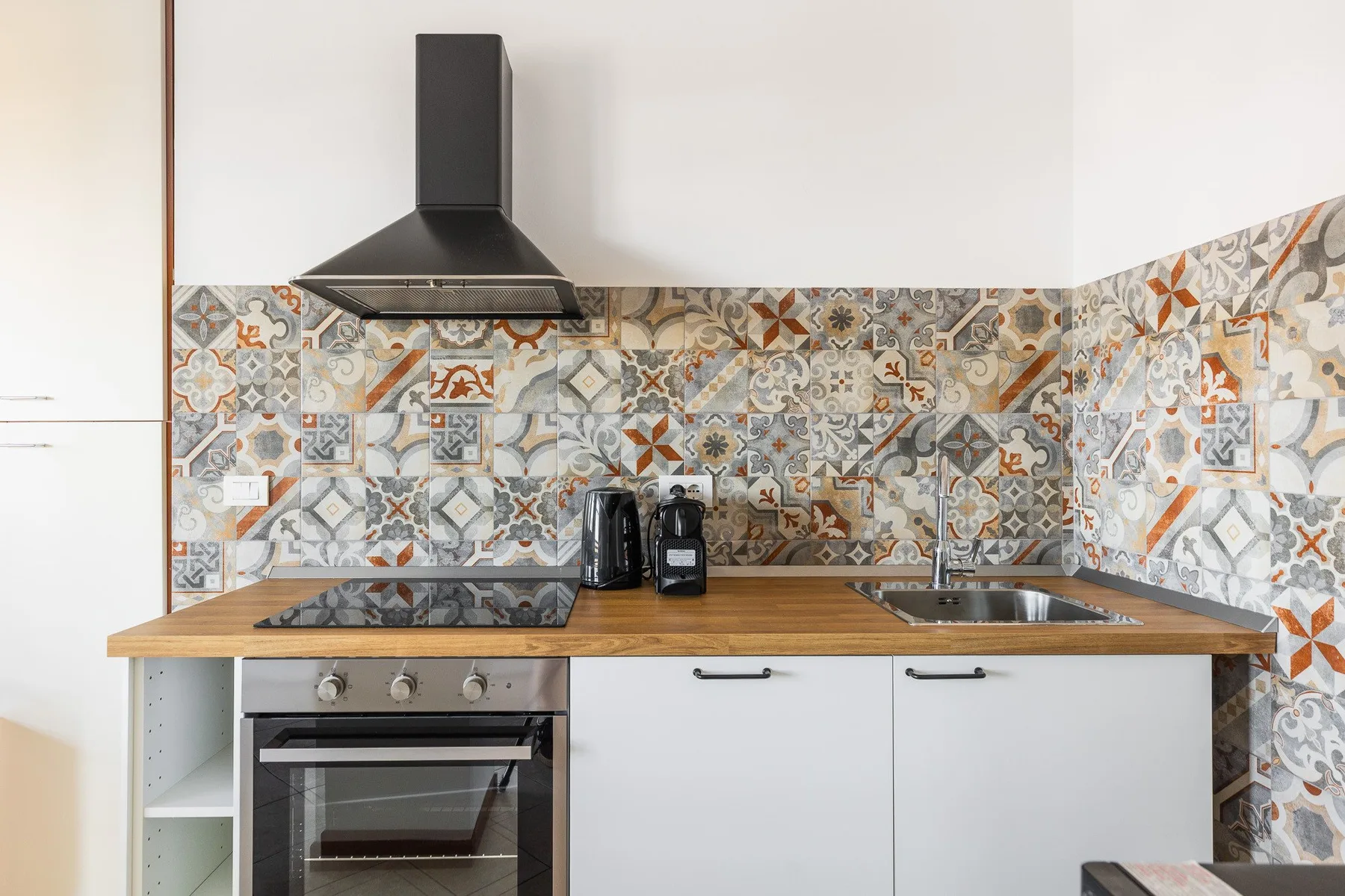 Una cocina con encimera de madera, salpicadero estampado y electrodomésticos de acero inoxidable.