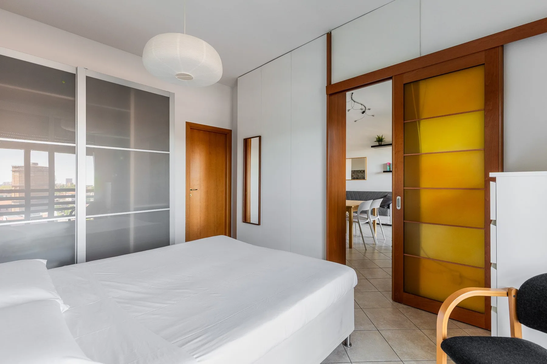 Un dormitorio con una cama y una puerta corredera abierta hacia un comedor.