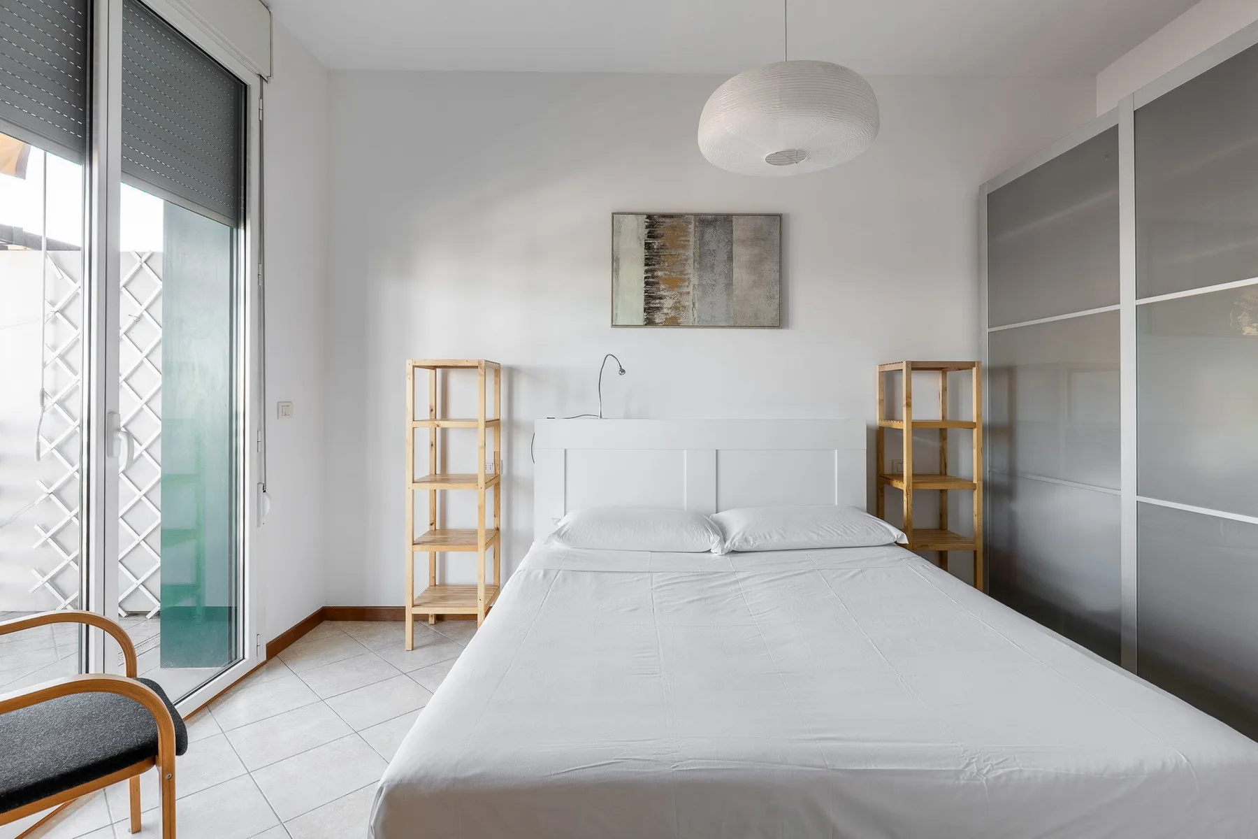 Un dormitorio luminoso con una cama tendida y grandes puertas de vidrio.