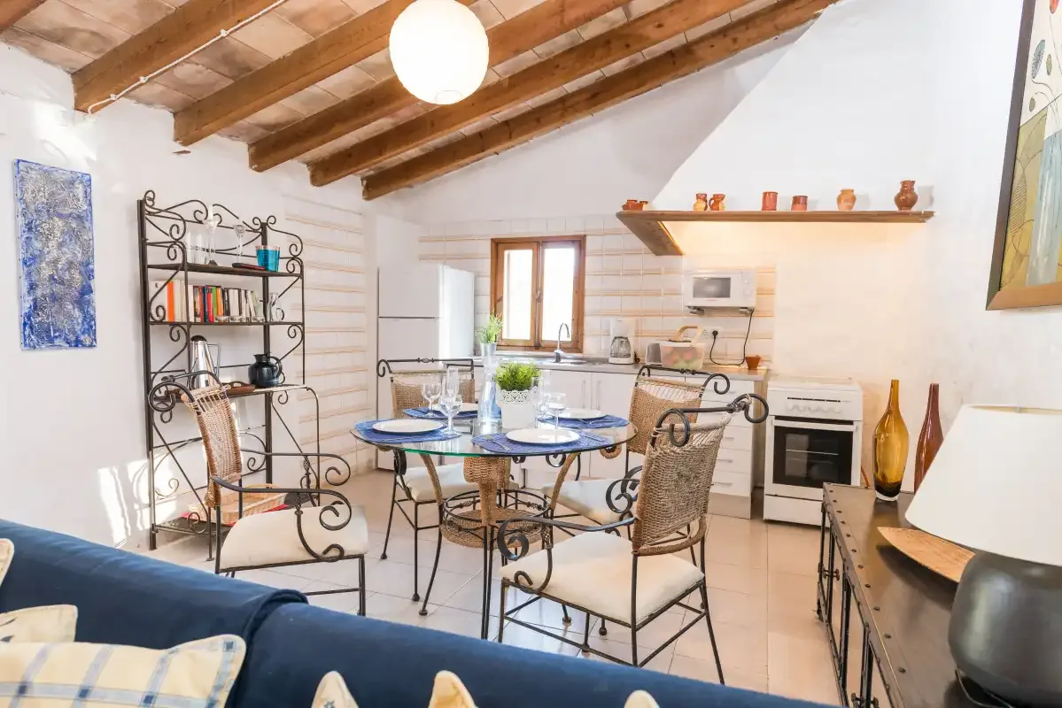 Un comedor con mesa y asientos junto a una cocina compacta.