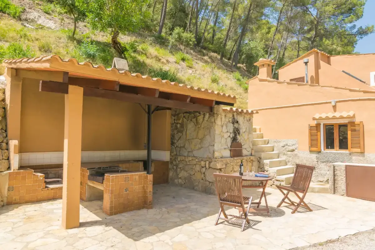 Un patio de piedra soleado con una zona cubierta para sentarse y escalones cercanos.