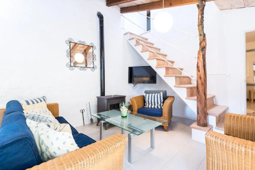 Una sala de estar luminosa con asientos alrededor de una mesa de centro de vidrio bajo una escalera.