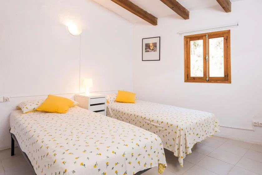 Un dormitorio con dos camas cubiertas con ropa de cama clara estampada.