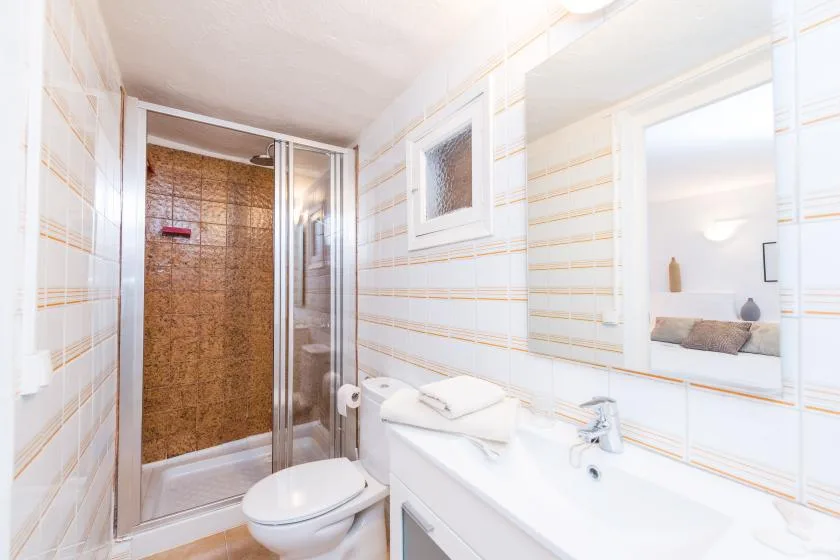 Un baño luminoso con ducha, inodoro y lavabo.
