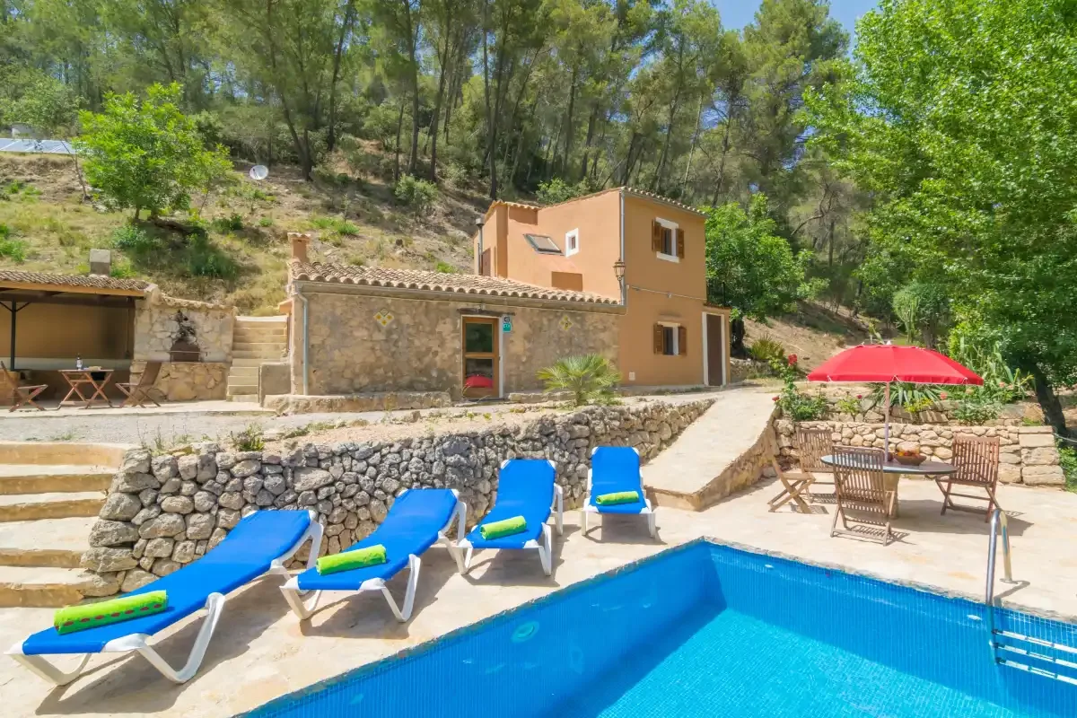 Una casa en la ladera da a una piscina con tumbonas y asientos al aire libre.