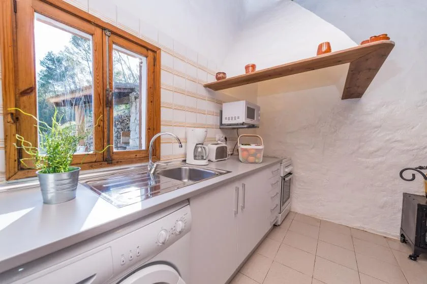 Una cocina pequeña con encimera, fregadero y ventanas con marcos de madera.