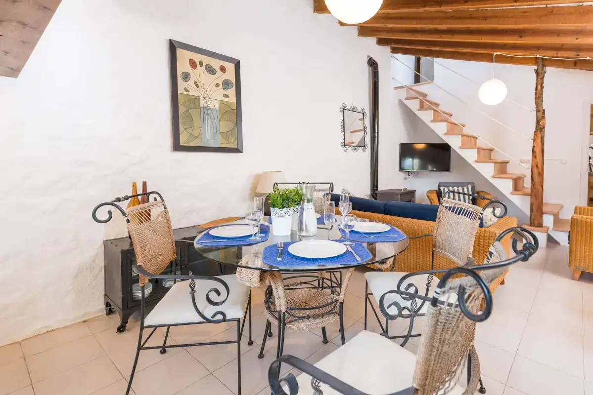 Un comedor con la mesa puesta y una escalera al fondo.
