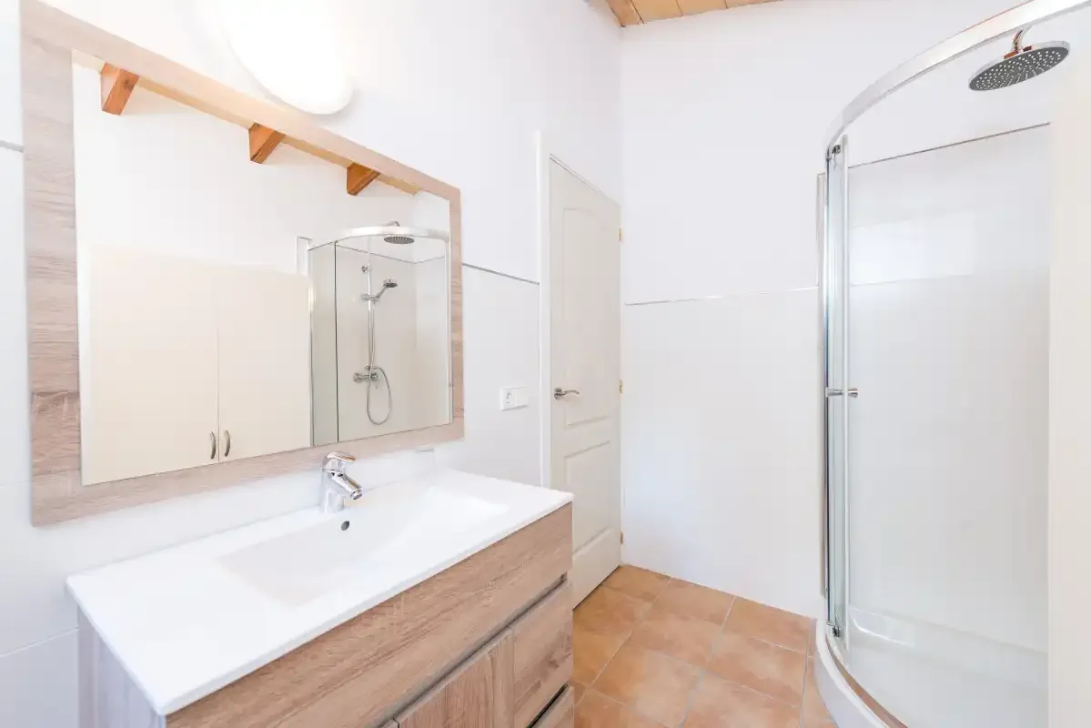 Un baño luminoso con lavabo, espejo y ducha.