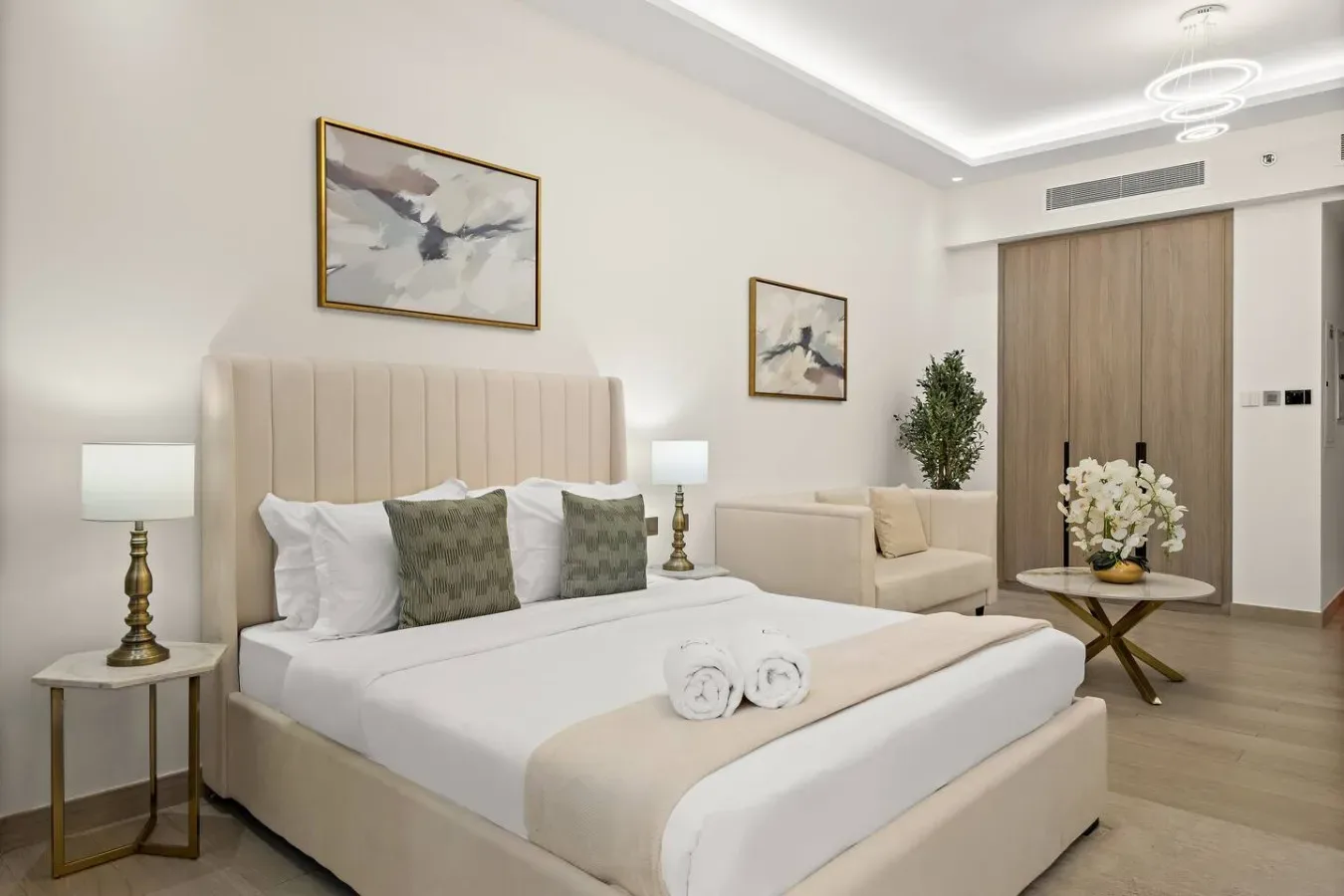 Un dormitorio luminoso con una cama tendida y una pequeña zona de estar.