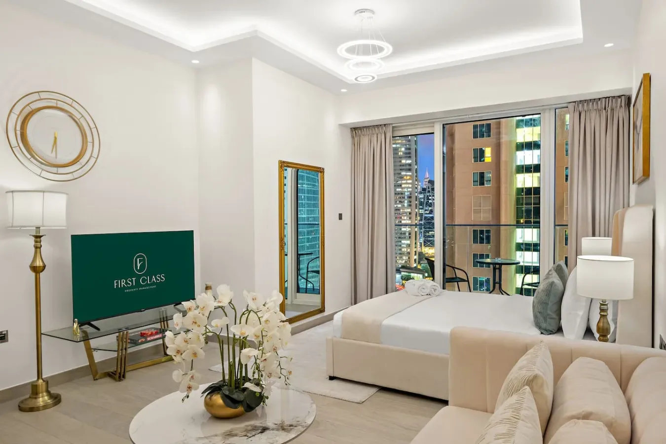 Una sala luminosa con asientos, un televisor y grandes ventanas con edificios de la ciudad a la vista.