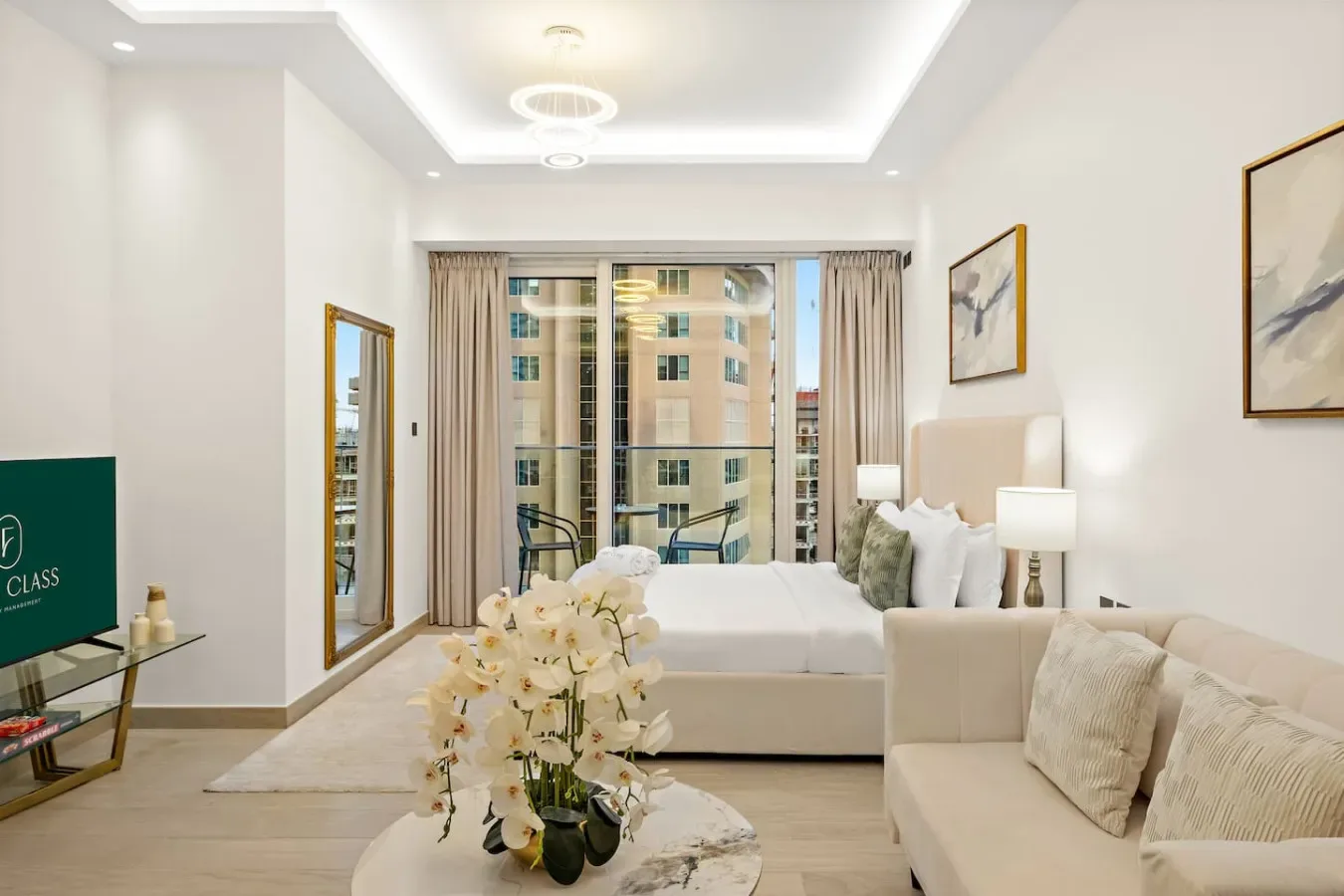 Un dormitorio luminoso con una cama, una zona de estar y grandes ventanas.