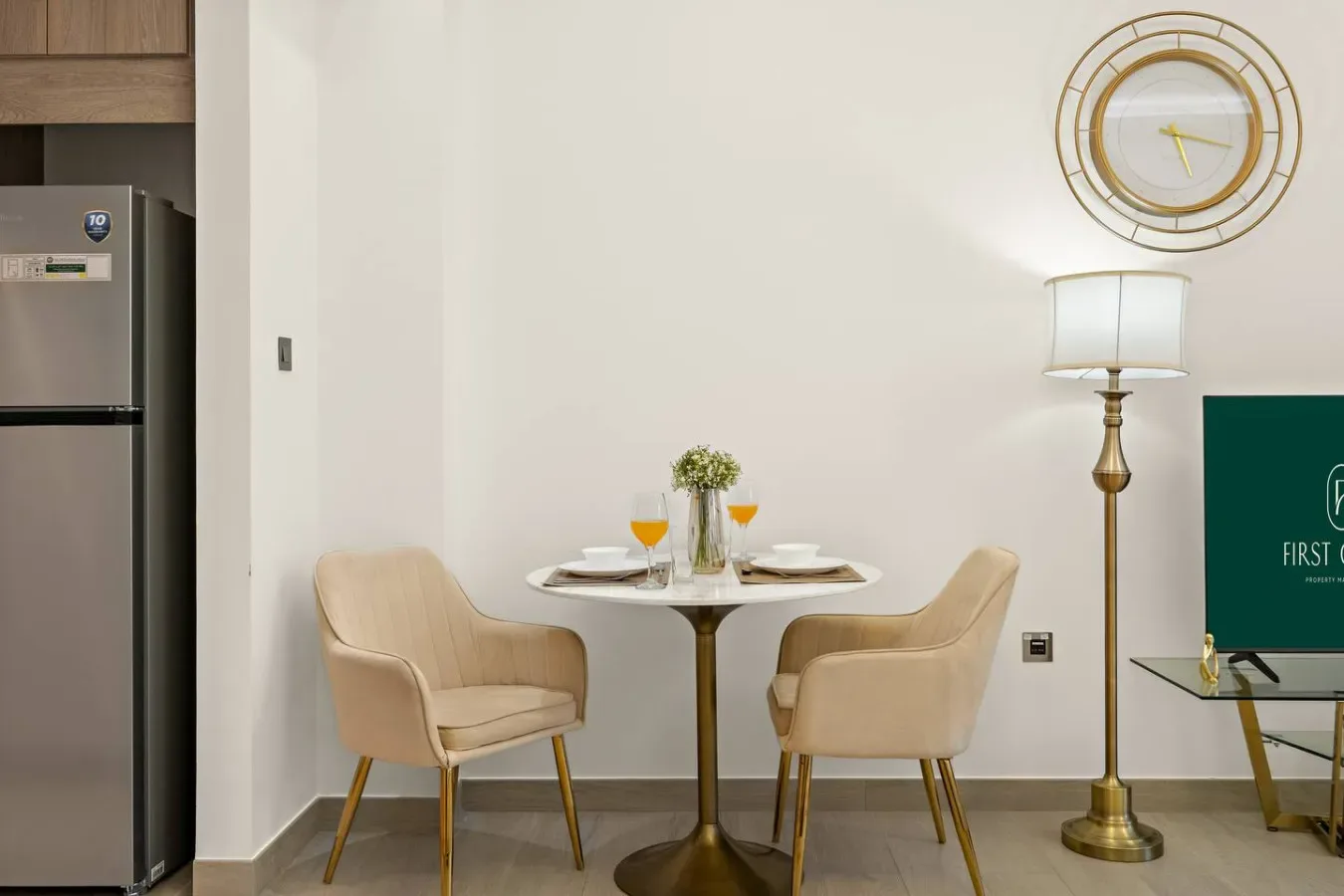 Un rincón de comedor con una mesa redonda pequeña y dos asientos tapizados.