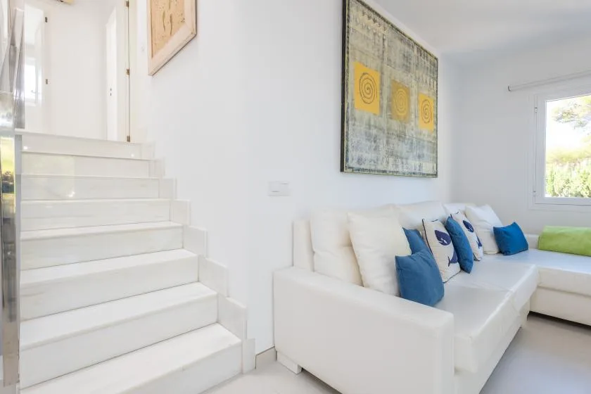 Una sala luminosa con asientos blancos y una escalera.