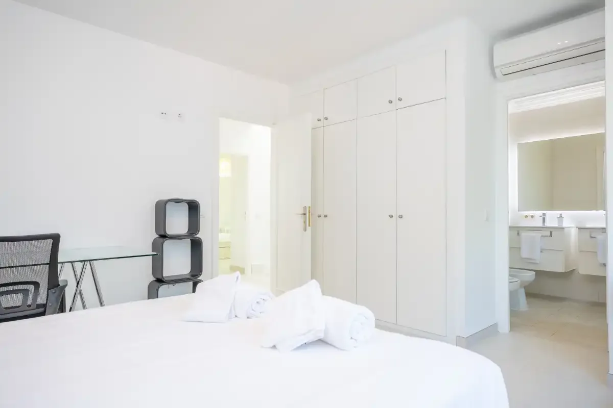 Un dormitorio luminoso con una cama bien tendida y armarios empotrados.
