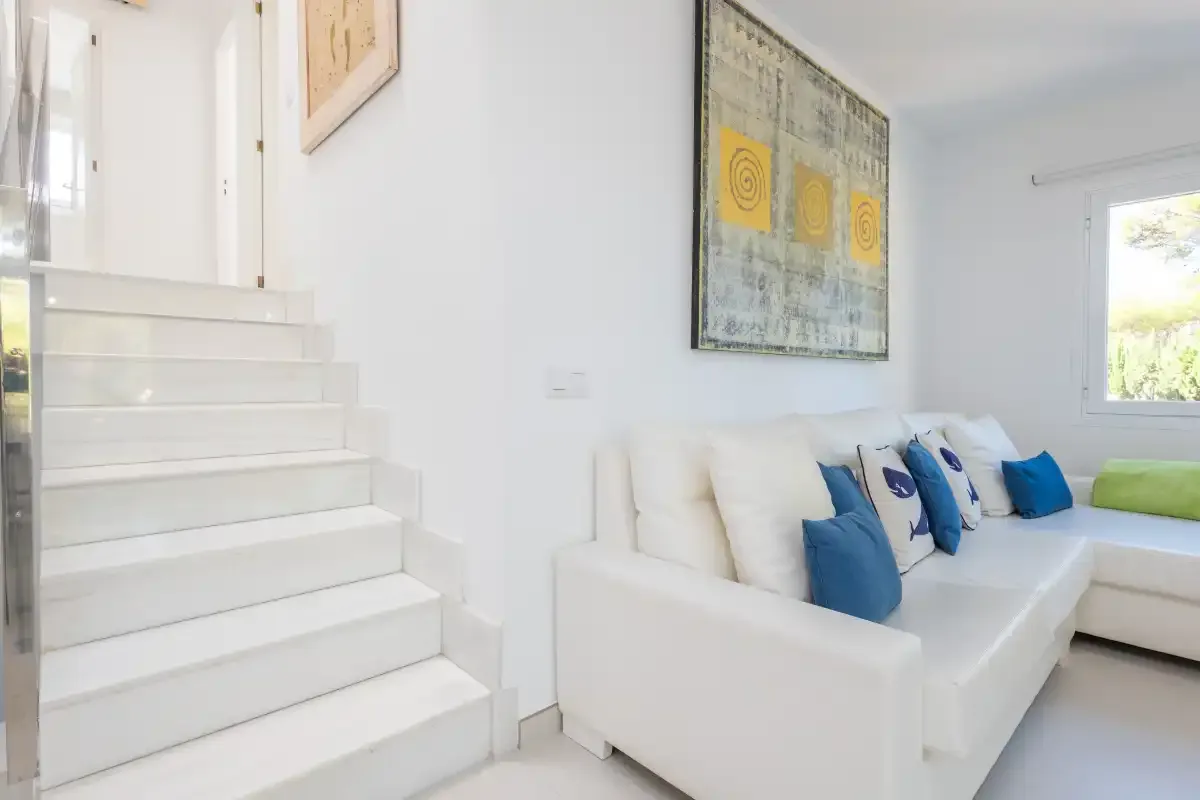 Una sala luminosa con asientos blancos y una escalera.