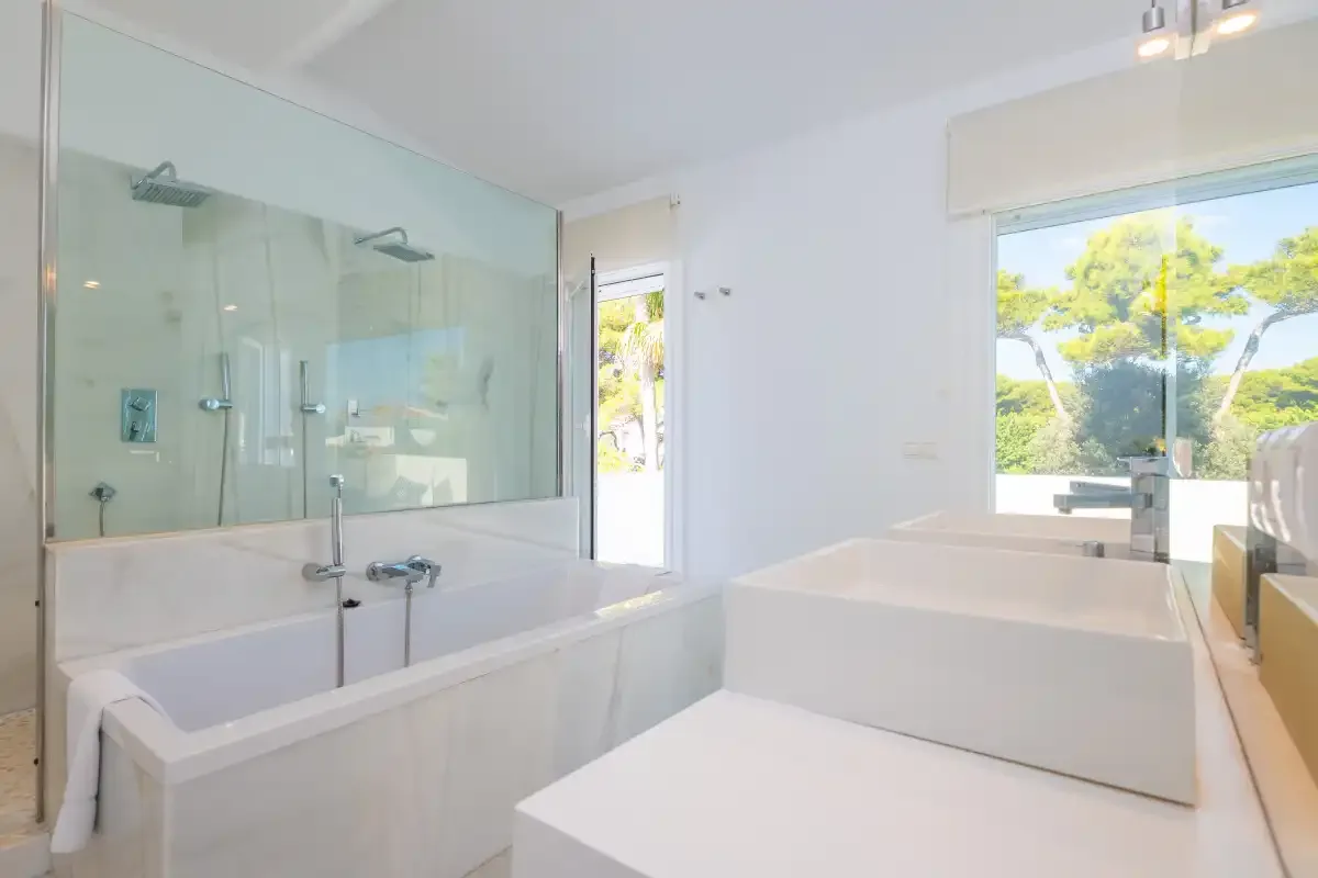 Un baño luminoso cuenta con bañera, ducha y una ventana amplia.