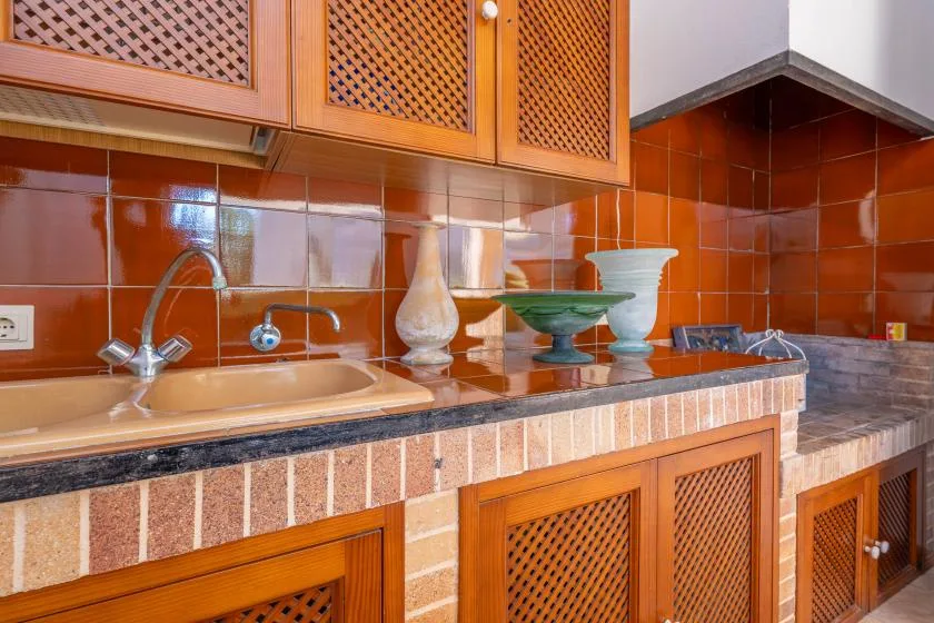 Una encimera de cocina con azulejos, fregadero, grifo y armarios de madera.