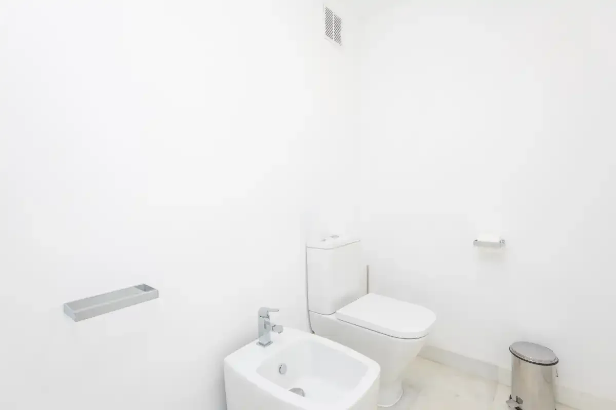 Un baño luminoso con inodoro, bidé y lavabo.