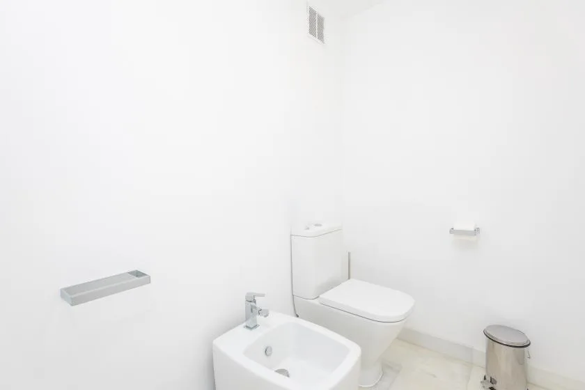 Un baño luminoso con inodoro, bidé y lavabo.