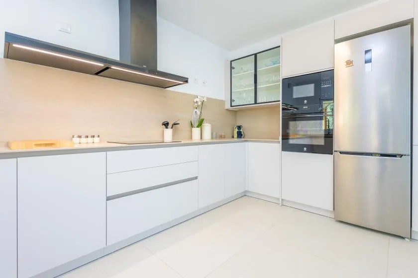 Una cocina moderna con gabinetes blancos, una encimera y electrodomésticos de acero inoxidable.