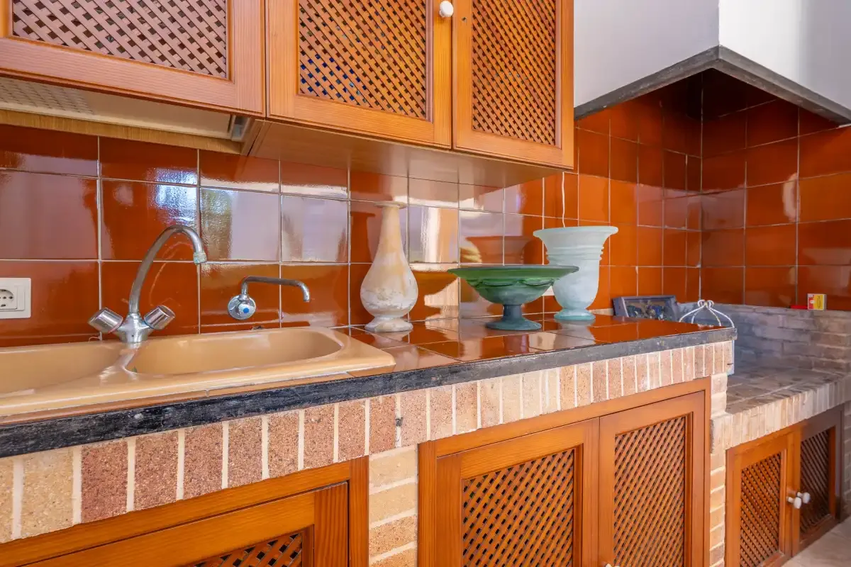 Una encimera de cocina alicatada con fregadero y armarios de madera arriba y abajo.