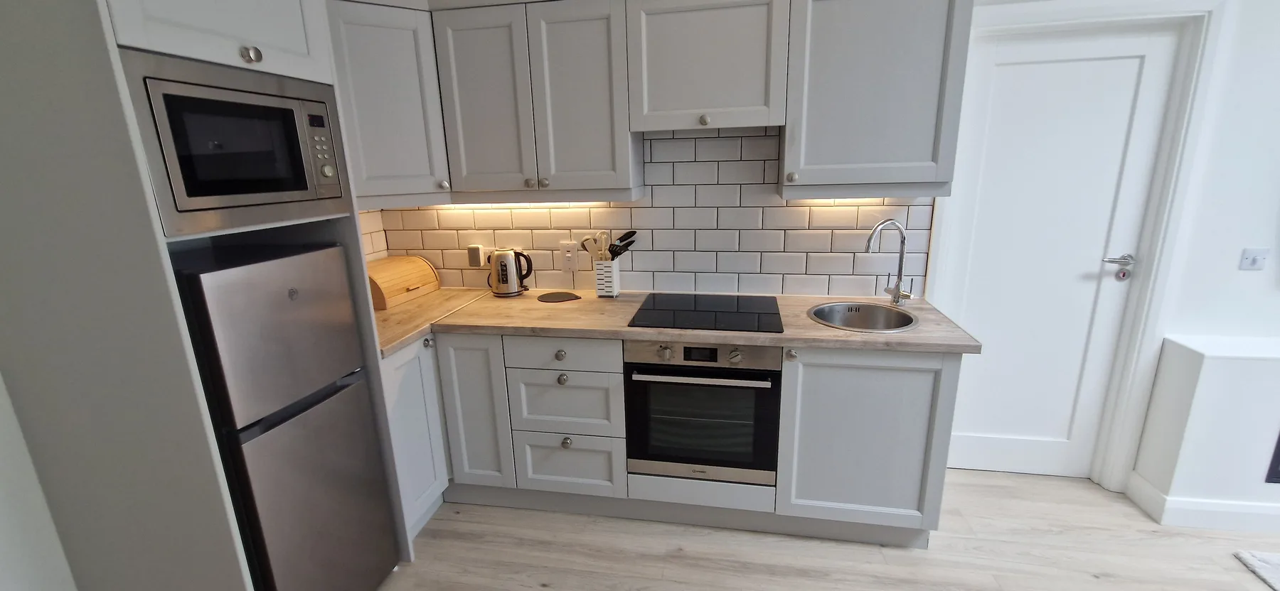 A fitted kitchen with pale cabinets, a built-in oven, and a countertop sink.
