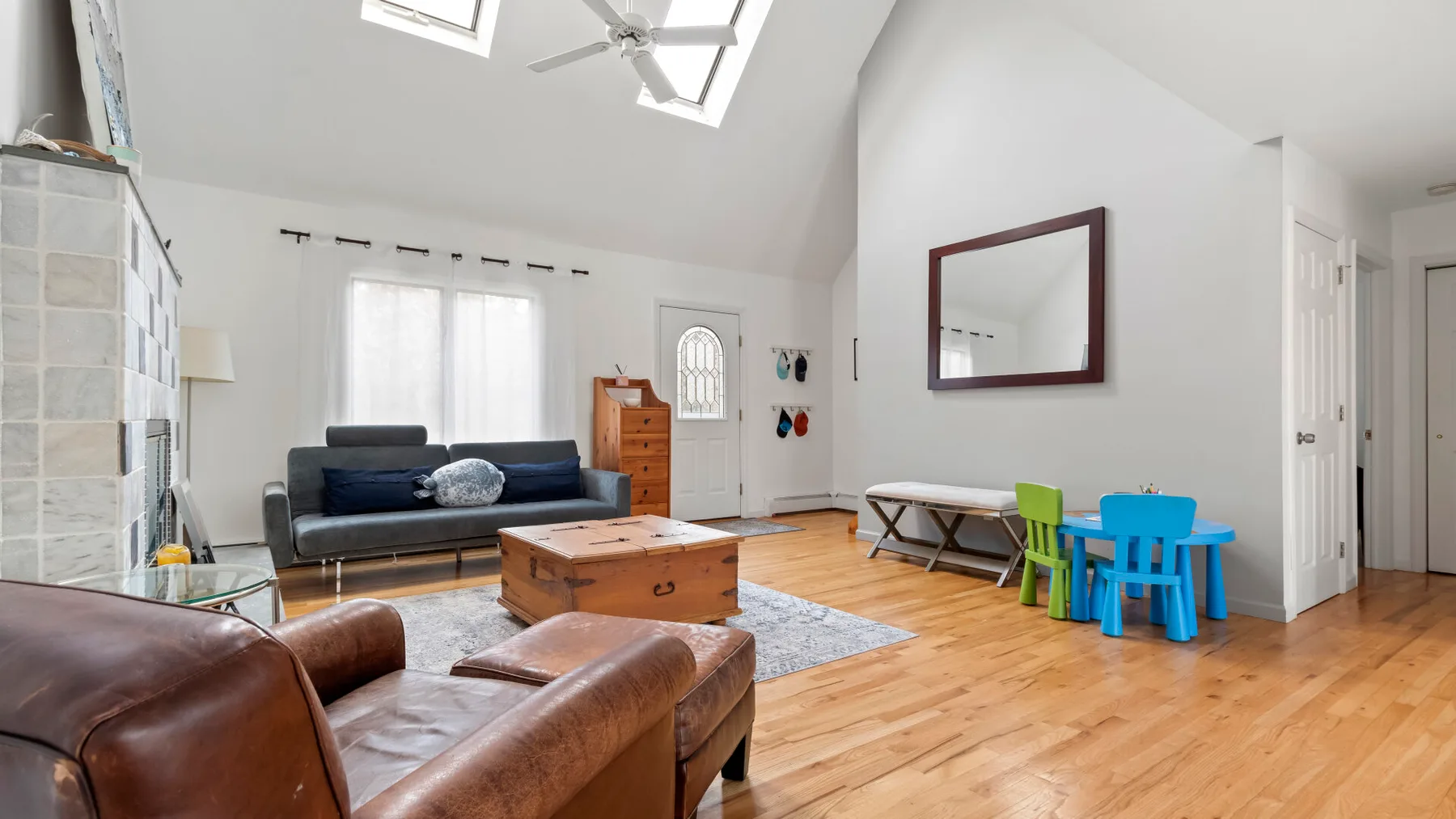 A bright living room with seating, a wooden coffee table, and a small children's table.