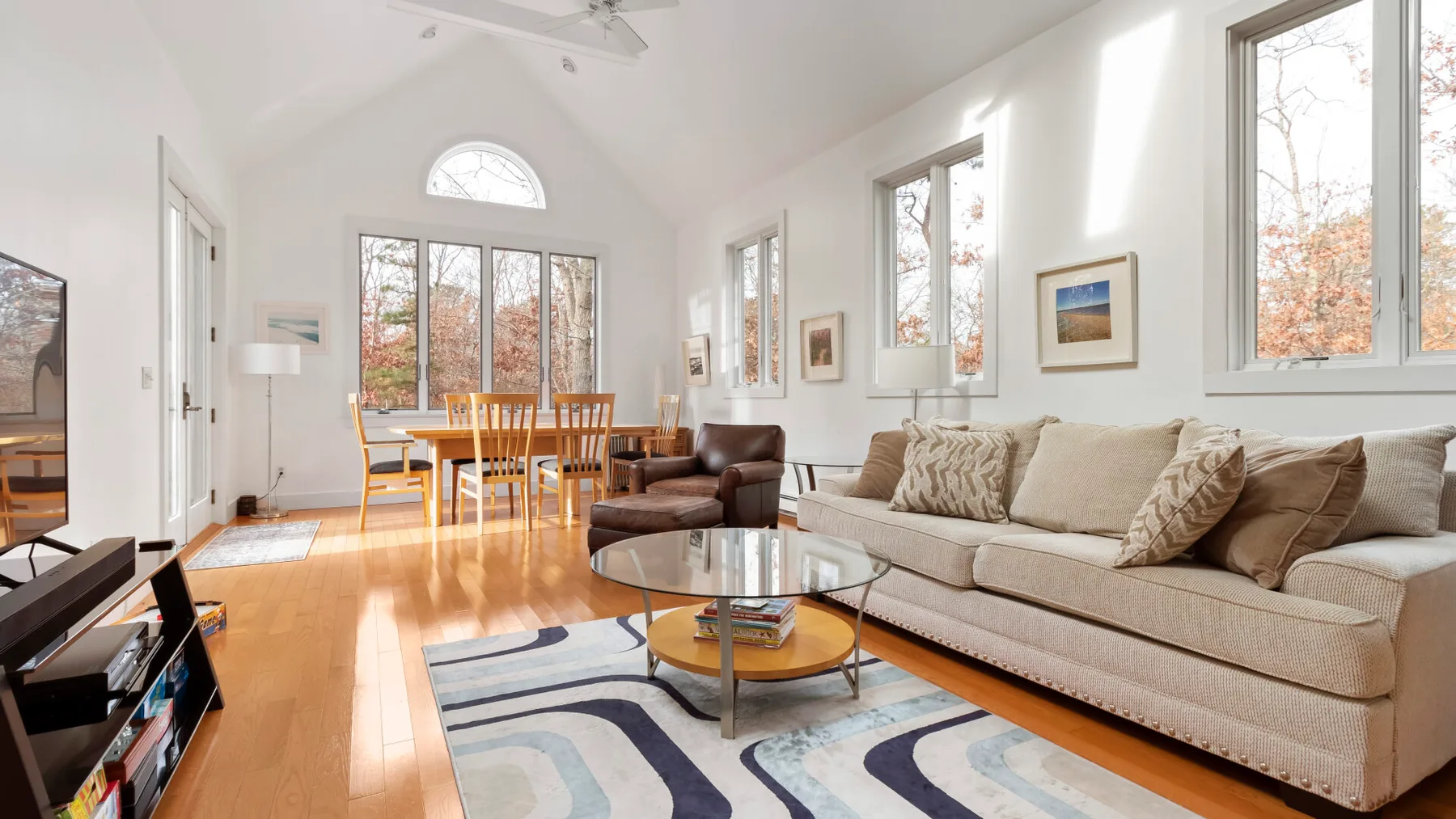A bright living room with seating, a coffee table, and a dining area by the windows.