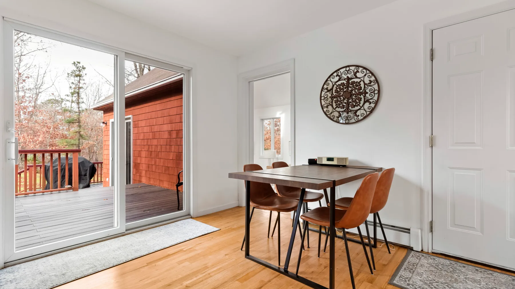 A dining area with a table and chairs beside sliding glass doors opening onto a deck.