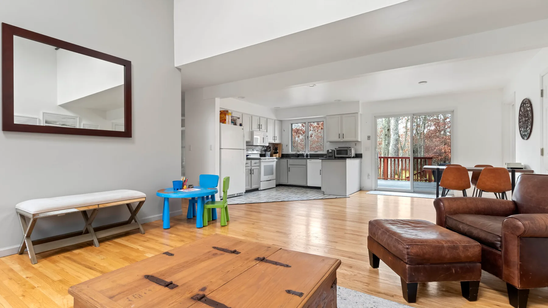 A bright open-plan living room and kitchen with a wooden coffee table.
