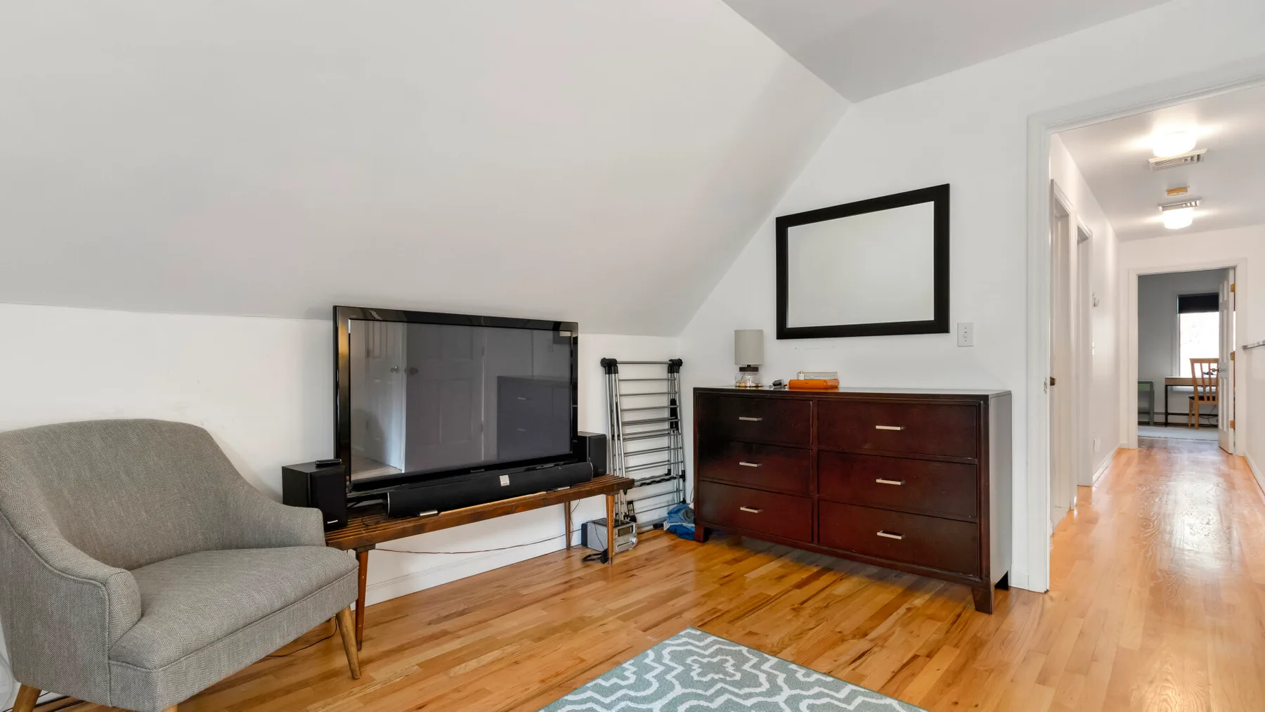 A bright living area with a television, seating, and a wooden dresser.