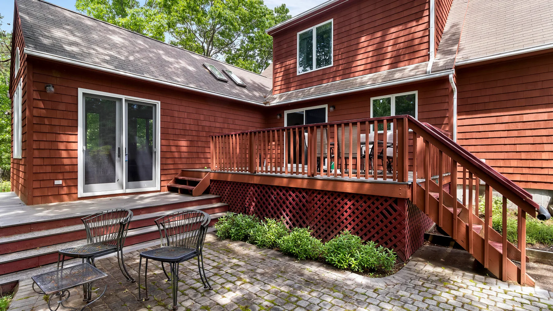 A red house with a wooden deck and patio seating.