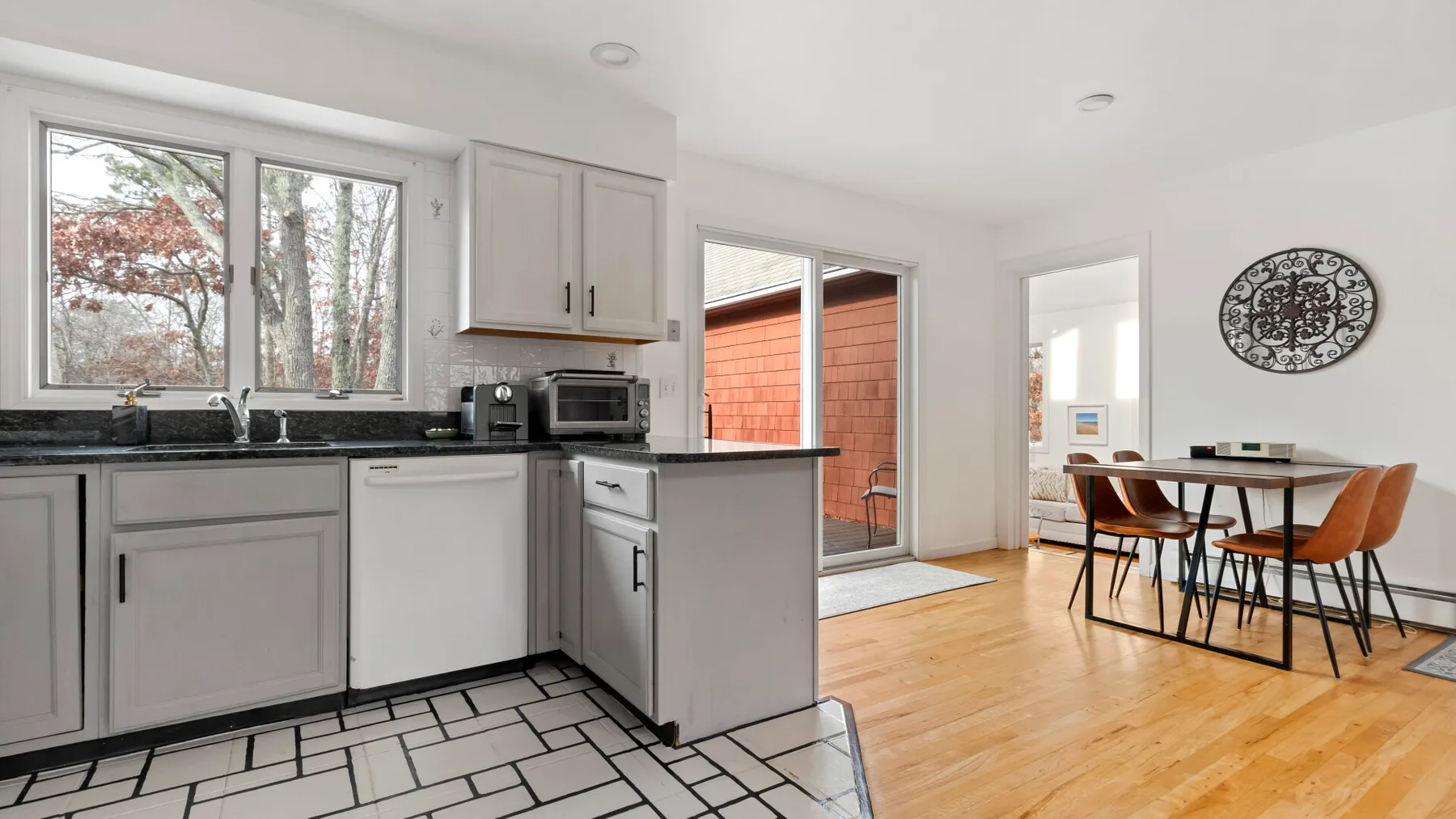 A bright kitchen opens onto a dining area with a wooden table.
