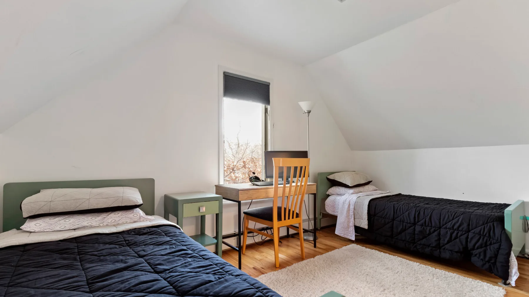A bedroom with two beds, a window, and a wooden chair.