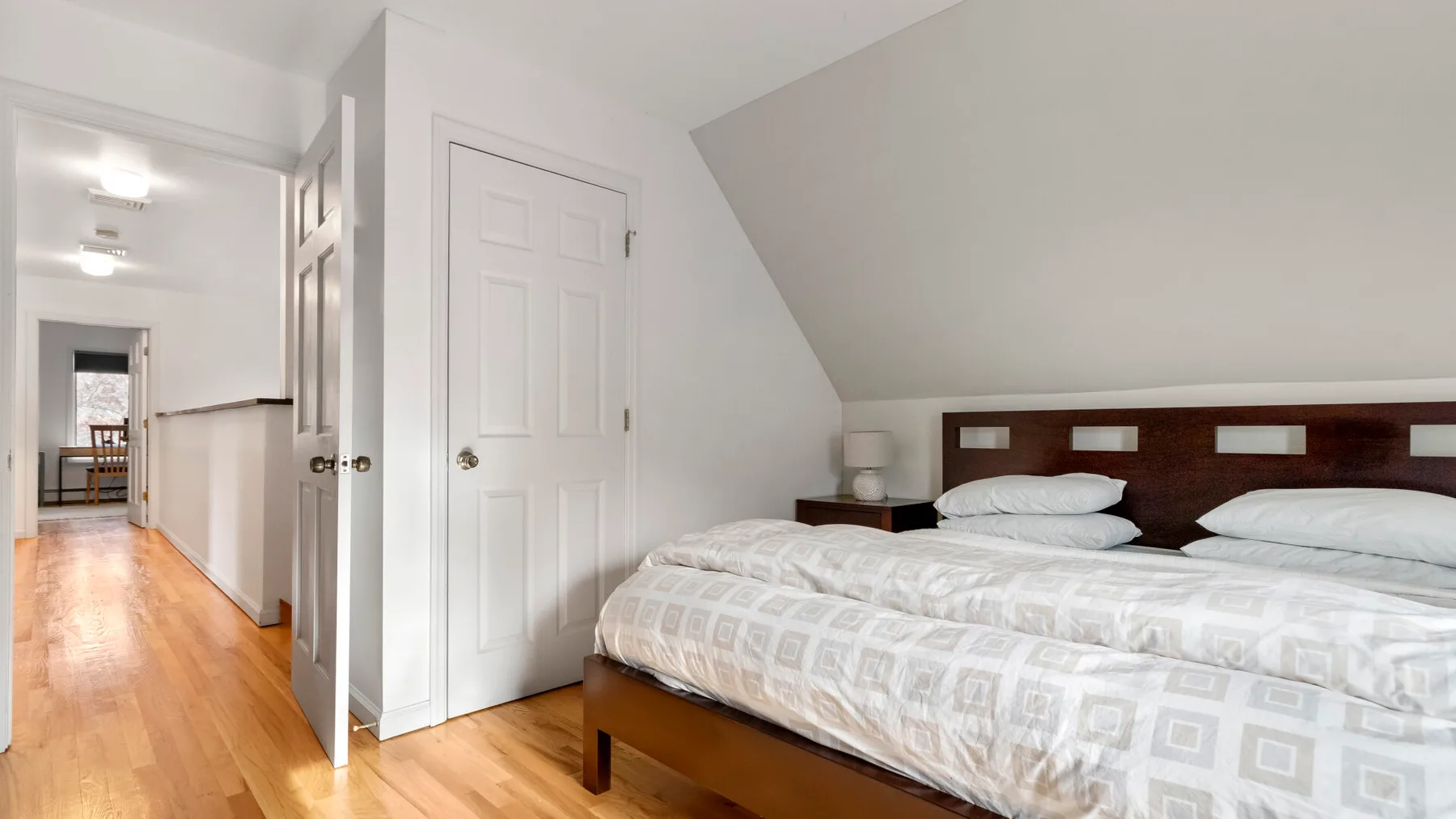 A bright bedroom with a bed beside a white paneled door.